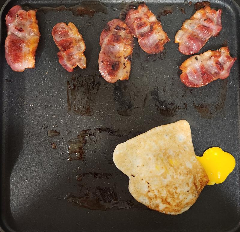 Cooking bacon and eggs for a breakfast sandwich