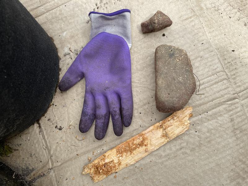 Photo of rocks and larger piece of much in comparison with gardening glove