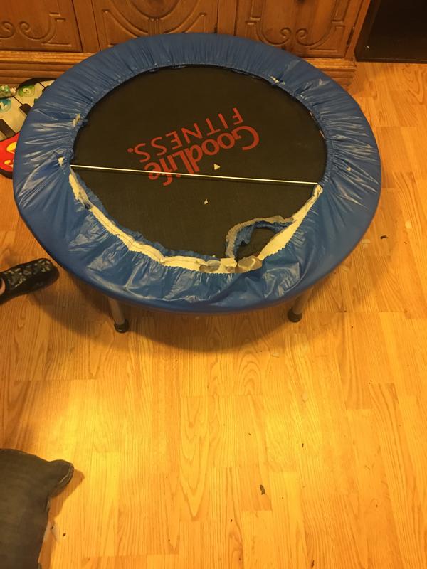 Picture of trampoline, covering of the springs is half torn with a line of elastic bisecting the top