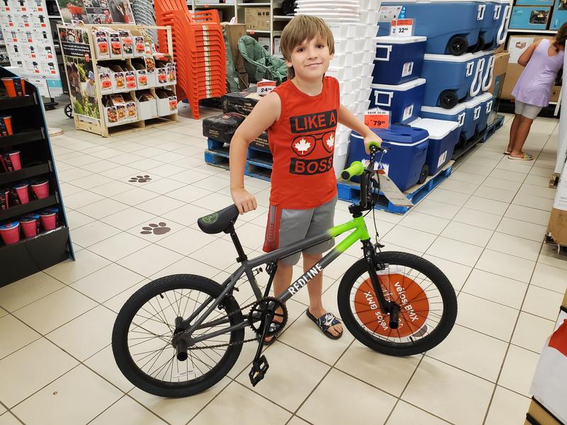 Walking his new bike up to the cash to pay for it with his hard earned money