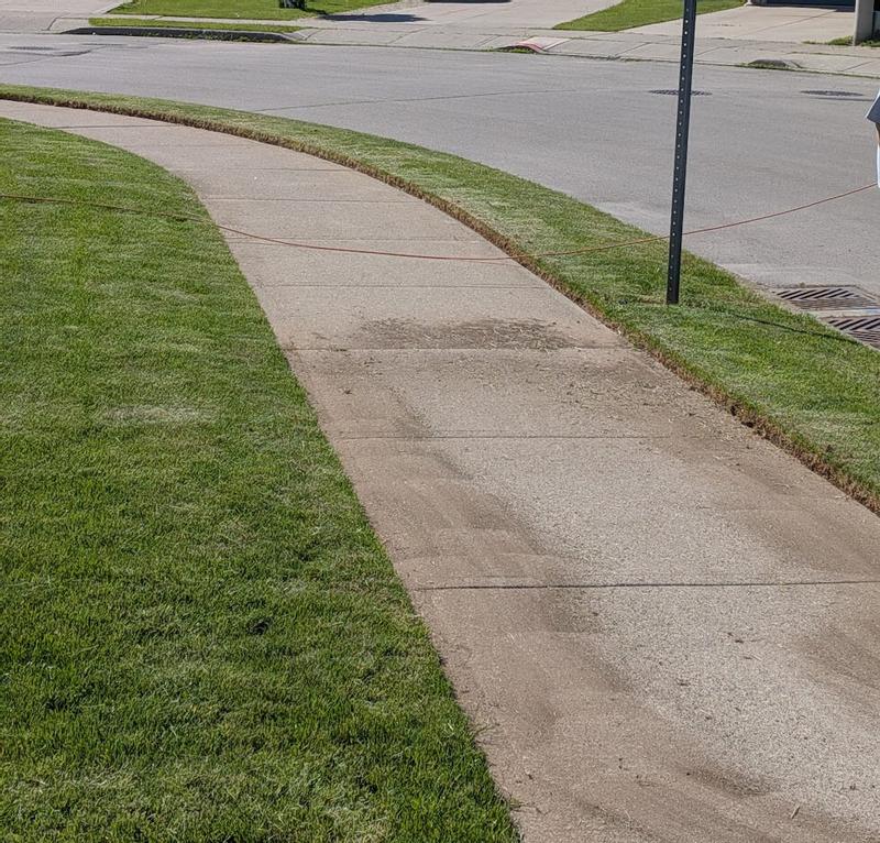 Clean edge on grass that is high compared to the sidewalk