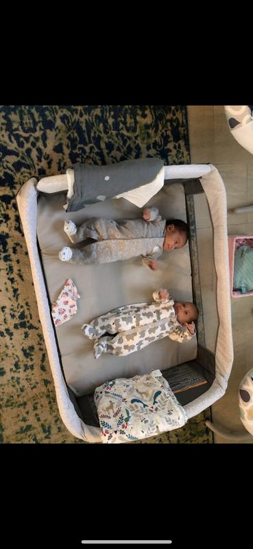 The twins in the bassinet play yard taking a nap.