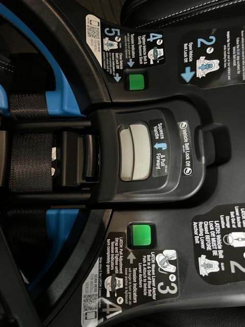 Red to Green indicators to say the seat belt is tight.| Seat hanging between captain's chairs while installing.| Rear Facing| Rotated toward the door.| Wire that connects the seat to the base.