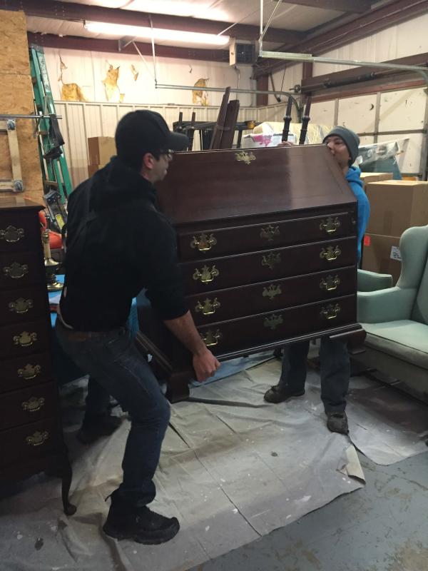 Crew members lifting customers dresser in warehous