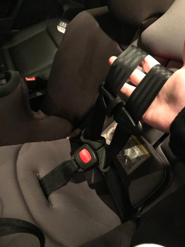 Tightens at the bottom by the red buckle not by the shoulders