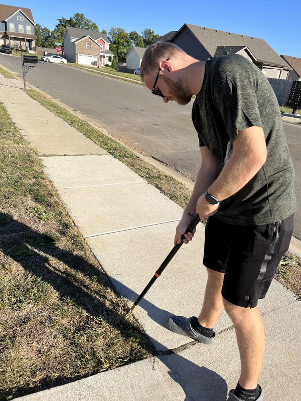 My husband using the weeder in the sidewalk