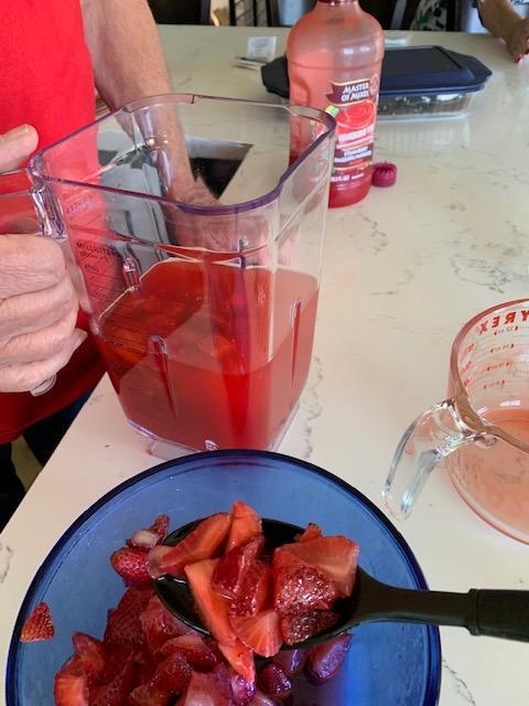 Adding Strawberries to the margaritas.
