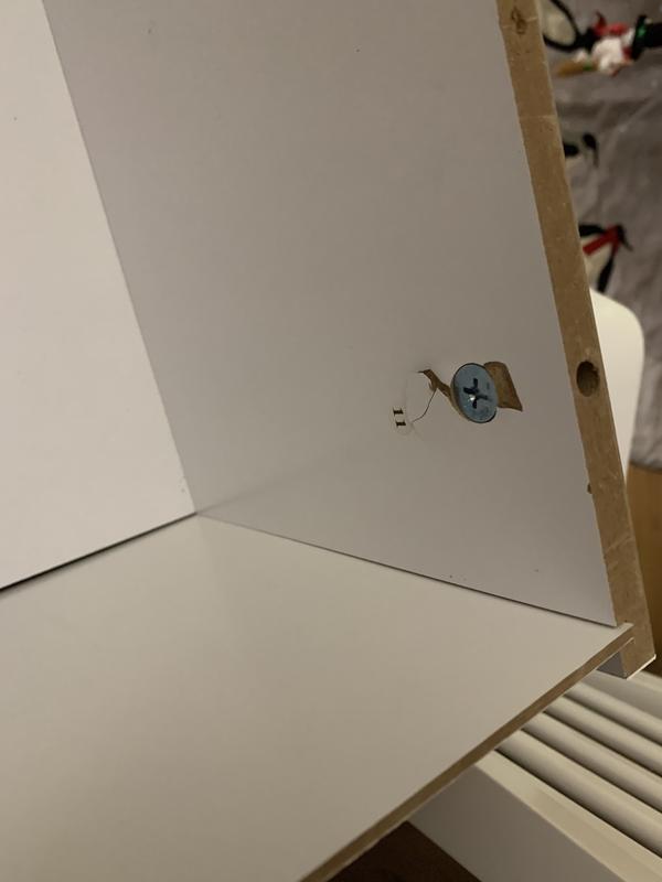 Inside the cabinet of the desk.  Screw was screwed into the correct play.  It split the wood.