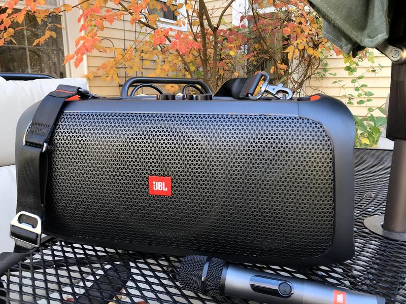 Front view of speaker with microphone and bottle opener visible on strap.