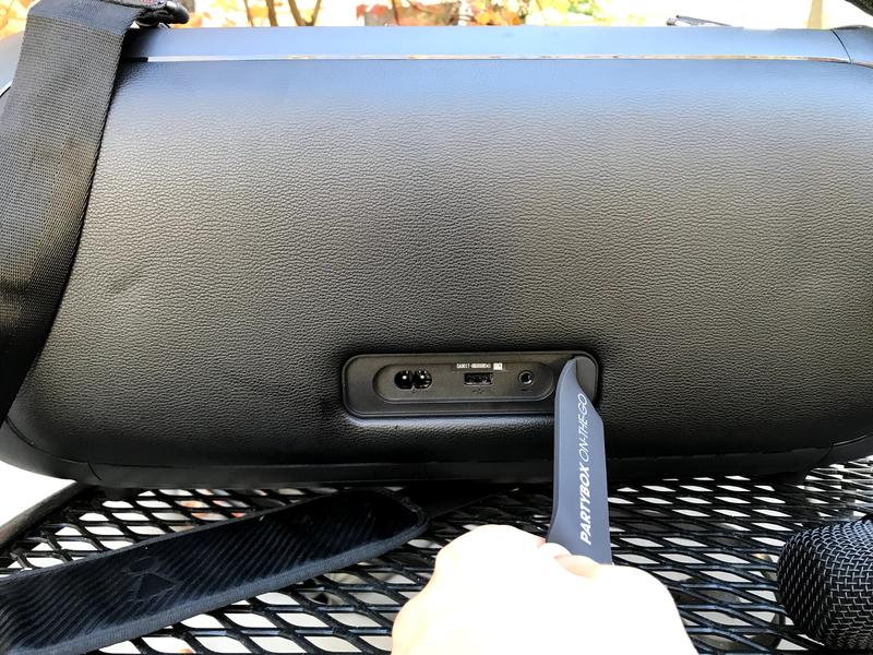 Back view of the speaker showing the charging port, USB port, and AUX port with removable cover.