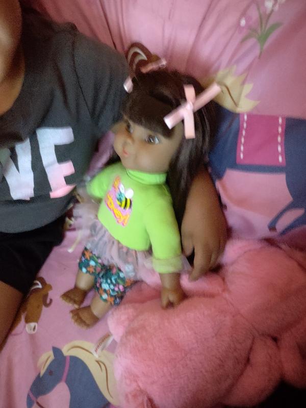 My daughter sitting with her doll on the bed