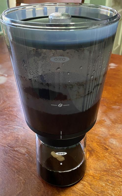Coffee has finished brewing and is draining into the glass carafe.