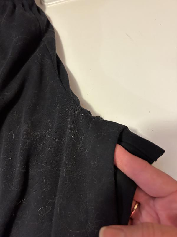 Old sport knit pants under new sport knit pants, at the rise.  New sport knit pants shrunk to where the rise is nearly 2” shorter than old pants. Old pants are under my hand.  Finger pointing edge of rise in new sport knit pants. Shrunk like cheap clothes