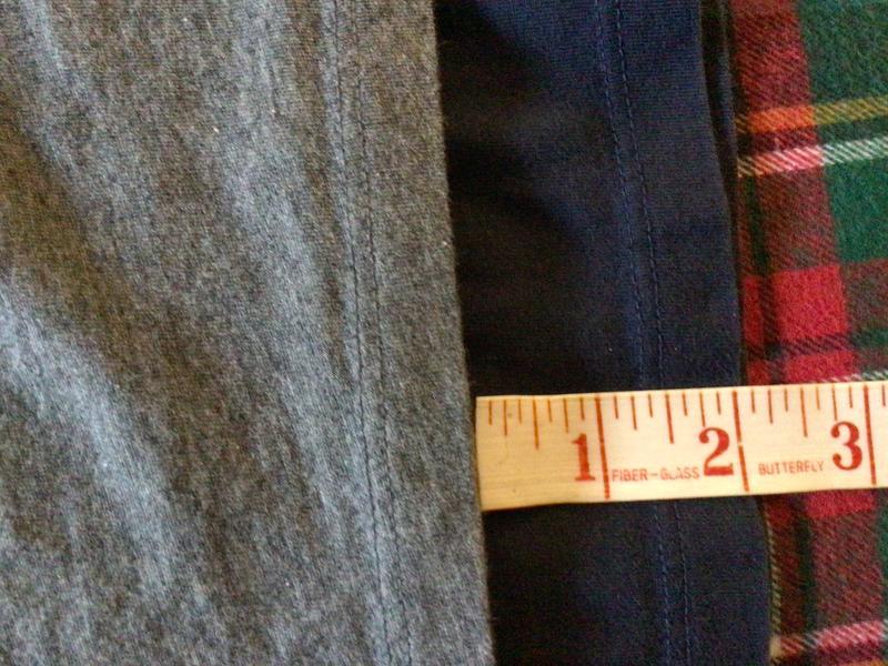 Navy shirt purchased about two years ago vs. gray one recently purchased- 2” shorter. I measured from underarm seam to bottom of shirt.