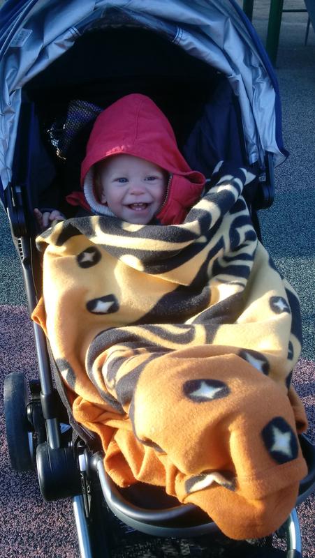 Warm on the playground in his red coat and Pacific northwest sun blanket