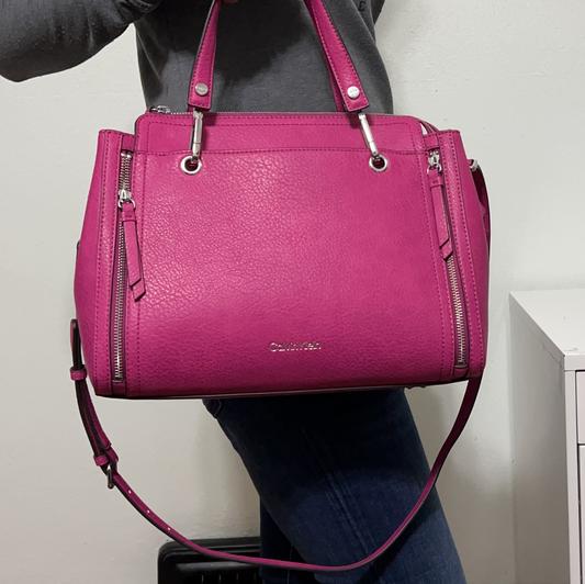 Holding the satchel by the handles