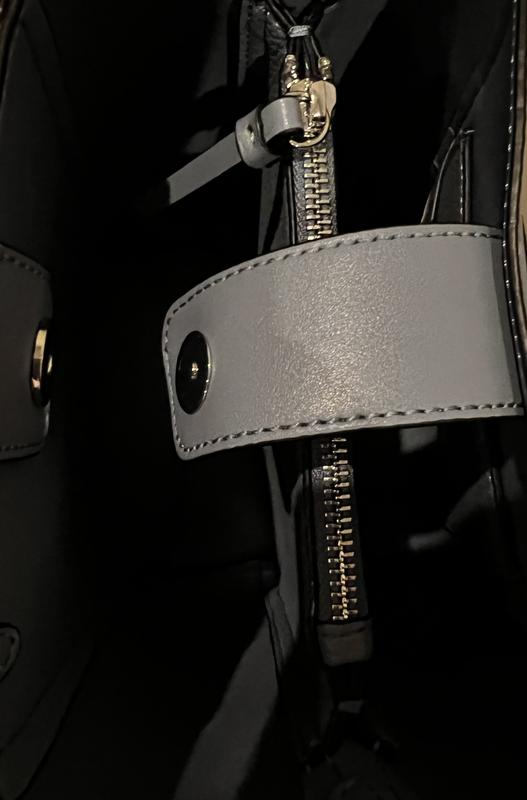 Inside of the handbag showing the closure and inner zipper compartment.
