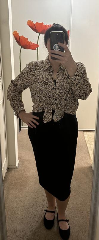 Shirt worn tied at waist over a black tan dress.