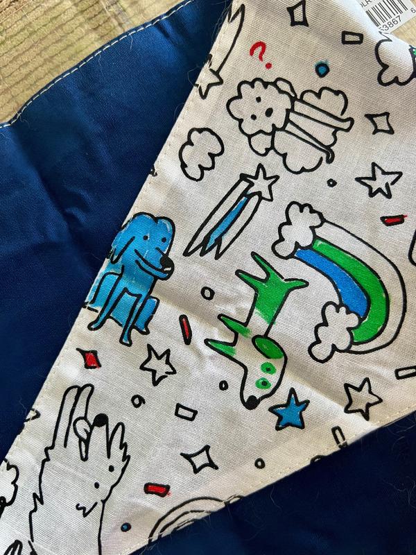 Bandana.  The inside is a dark blue.  The outside features a print of dogs, rainbows, shooting stars, and confetti.  It is in the process of being coloured in.