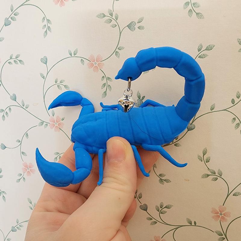 A hand holding the toy up against a floral wallpaper.