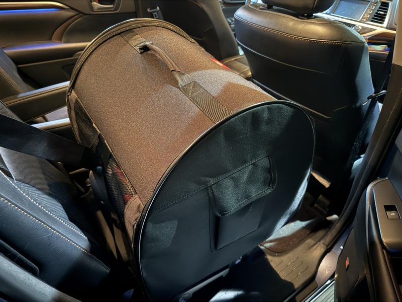 The all black crate is seat belted in the car.