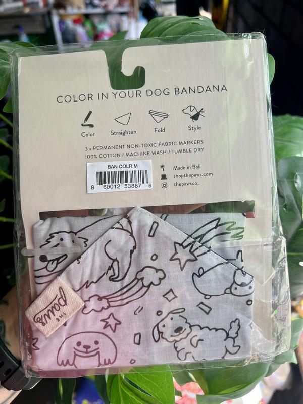Bandana in the product box showing the back.  The outside features a print of dogs, rainbows, shooting stars, and confetti.  It is meant to be coloured in with the included markers.