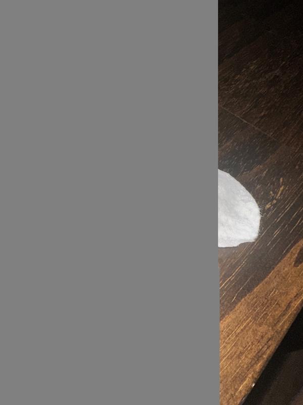 The inside of the paper seal used to protect the product, showing one of the wipes that got stuck to the adhesive.