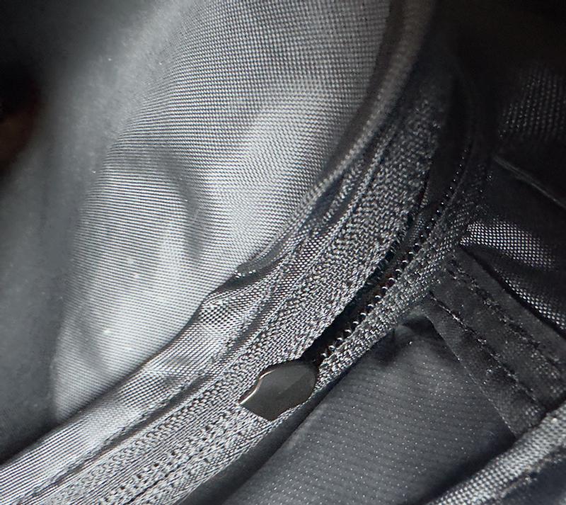 hidden zipper pull inside flap at back of bag, impossible to use easily