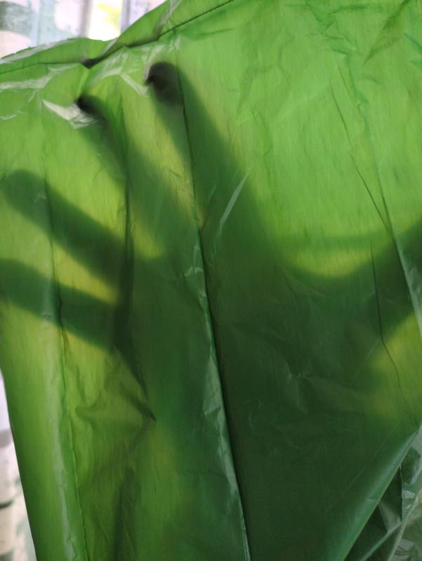 A hand sillouetted through a green plastic dookie bag