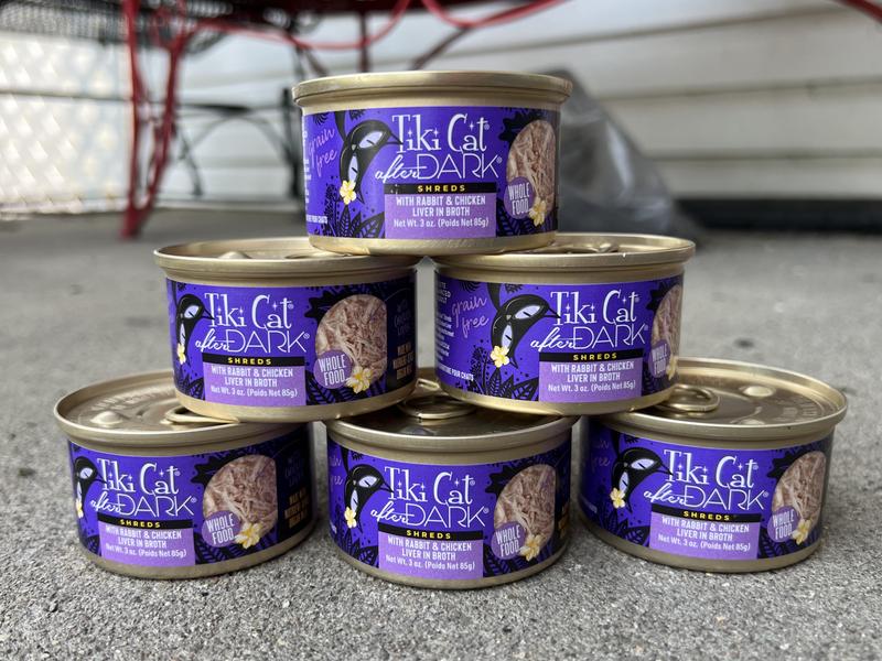 Six 3oz cans of Tiki Cat After Dark: Shreds With Rabbit and Chicken Liver in Broth.  They are stacked in a pyramid.