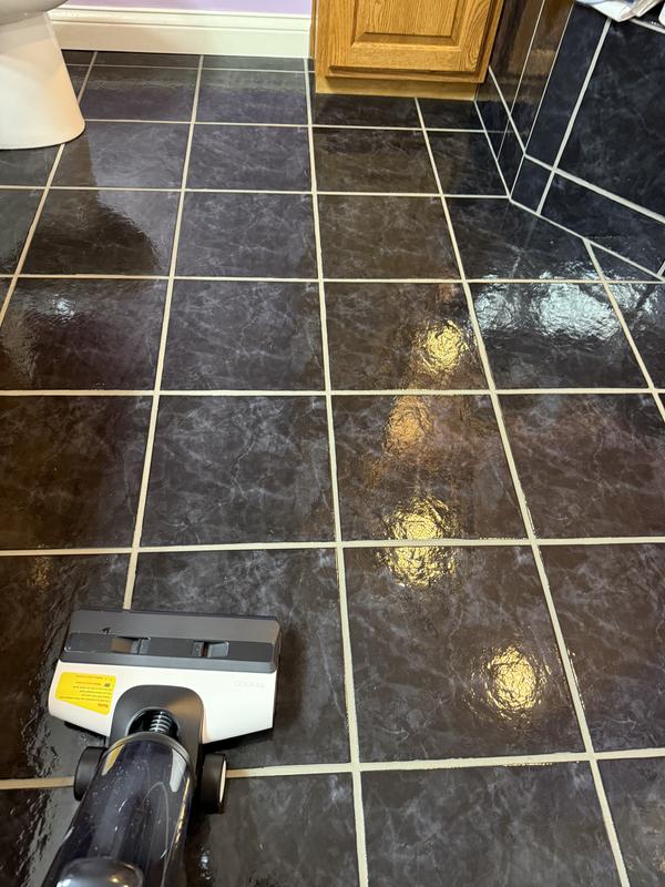 Before picture of shiny black tile with dirt on the floor