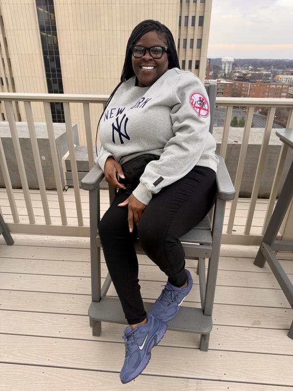 Comfort meets style blue Nikes on deck, city views behind, smiling and ready for all-day wear.