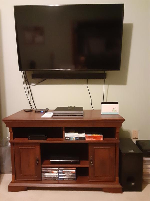 The soundbar is mounted right below the television while the subwoofer is to the right of the TV stand on the floor.