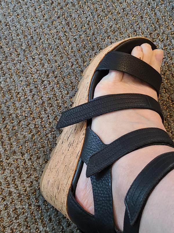 Longer left strap hangs over footbed