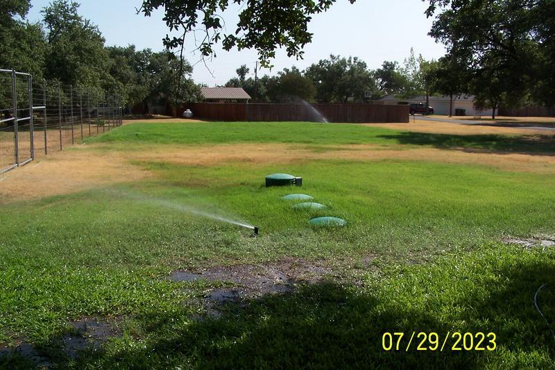 Drain field is in distance near brown fence
