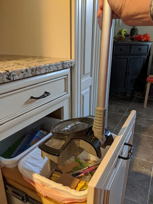 Lifting entire handle up above trash to empty.