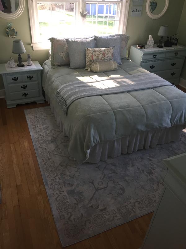 Rug in bedroom with light sage green walls and bed cover.