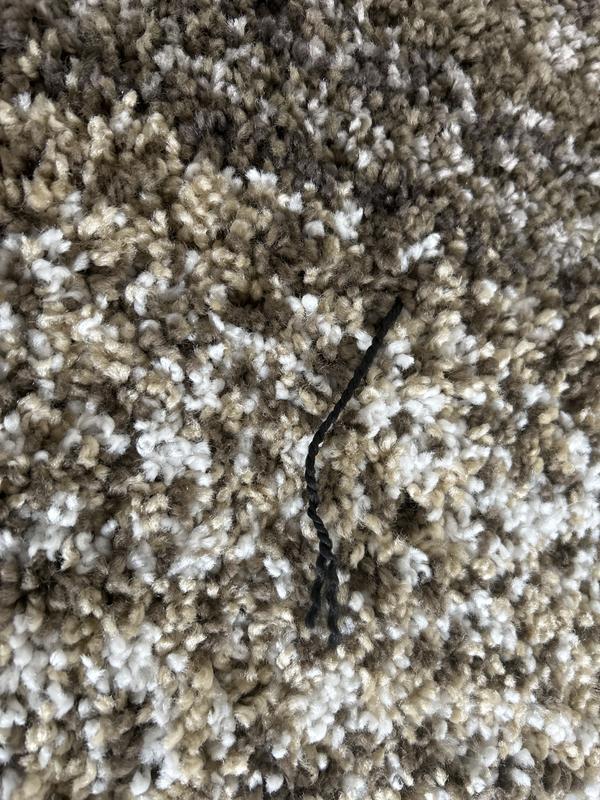 Multiple black strings pulling through the rug