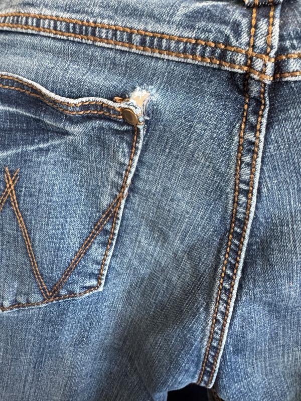 Tear at the left rear pocket rivet