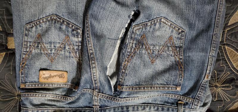 Huge tear, and Wrangler logo on back threading out