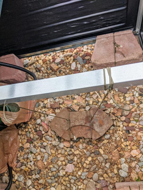 We used a tractor weight on the inside to stabilize it more from the wind, and added corner blocks in each corner. We also added redwood slats over the black plant trays.