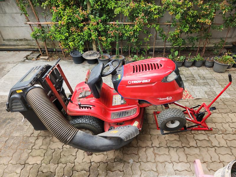 The mower raised up with a ProLift mower jack for blade maintenance.  The Bagger lid support is bolted to the mounting arms and has a rubber tube fixed to the top as a cushion.